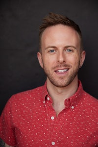 a man in a red shirt smiling for the camera